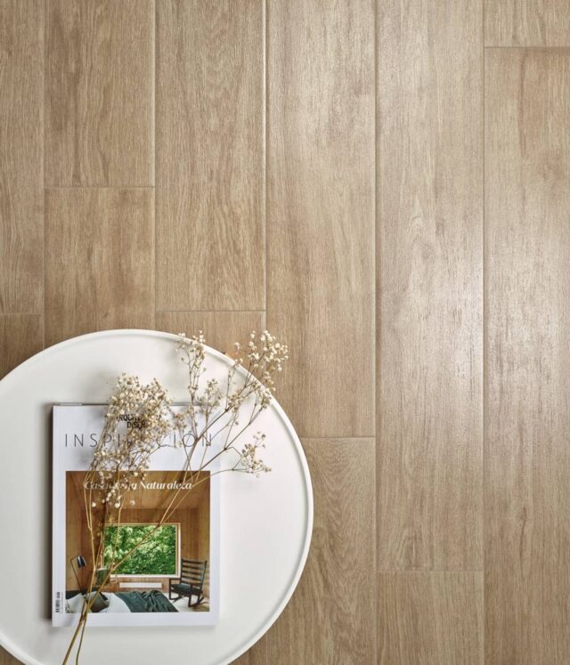 Table-with-magazine-and-dried-flower-seen-from-above-on-woodlike-floor-tiles