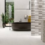 Bathroom-with-tall-sink-of-marble-effect-tiles-black-bathtub-and-plant
