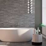 Modern bathroom with white tub, gray tile wall, large windows, and minimalist decor